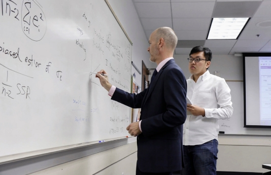 Dr. James Prieger writing on white board teaching School of Public Policy Student Aotian