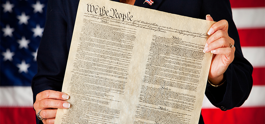 Man holding the Constitution in front of American Flag