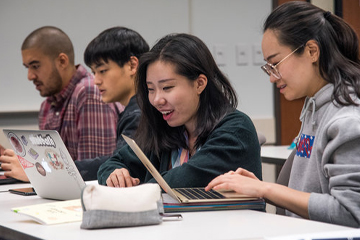 Students sitting in a classroom on their laptops