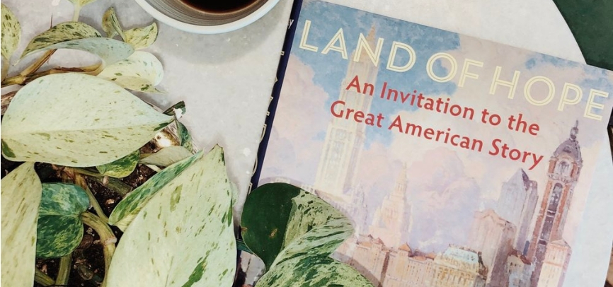 Wilfred McClay's Book next to a green plant and coffee cup 