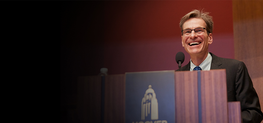 John Cochrane speaking at a podium